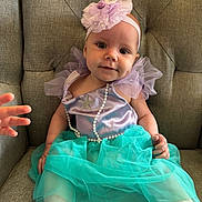 Iris is registered to the contest to win money with this photo: baby, chair, child, cute, foot, hand, happy, headband, indoors, mermaid_costume, pearl_necklace, person, portrait, purple_dress, smiling, soft_lighting, toddler, tufted_chair, tulle, turquoise_skirt