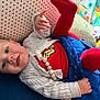 Iris joined the competition — help win amazing prizes! baby, blue_skirt, child, clothing, colorful, couch, cute, happy, indoor, infant, nursery, pacifier_clip, person, polka_dot_pillow, red_tights, smiling, superhero, toys, white_sweater, wonder_woman