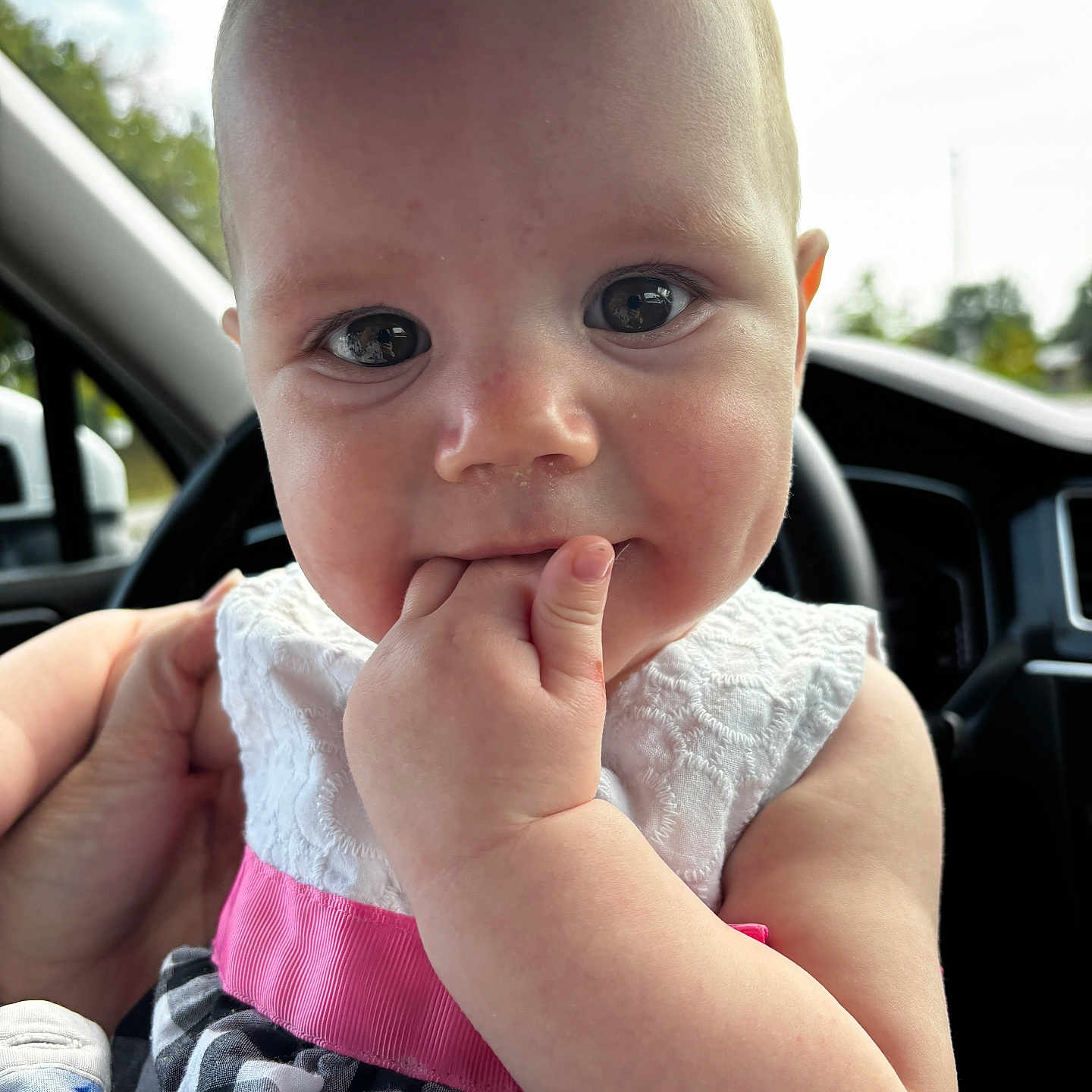Iris is registered to the contest to win money with this photo: baby, car_interior, cheeks, child, clothing, cute, daylight, dress, face, fingers, hand, holding, infant, person, pink, portrait, seat, skin, white, window