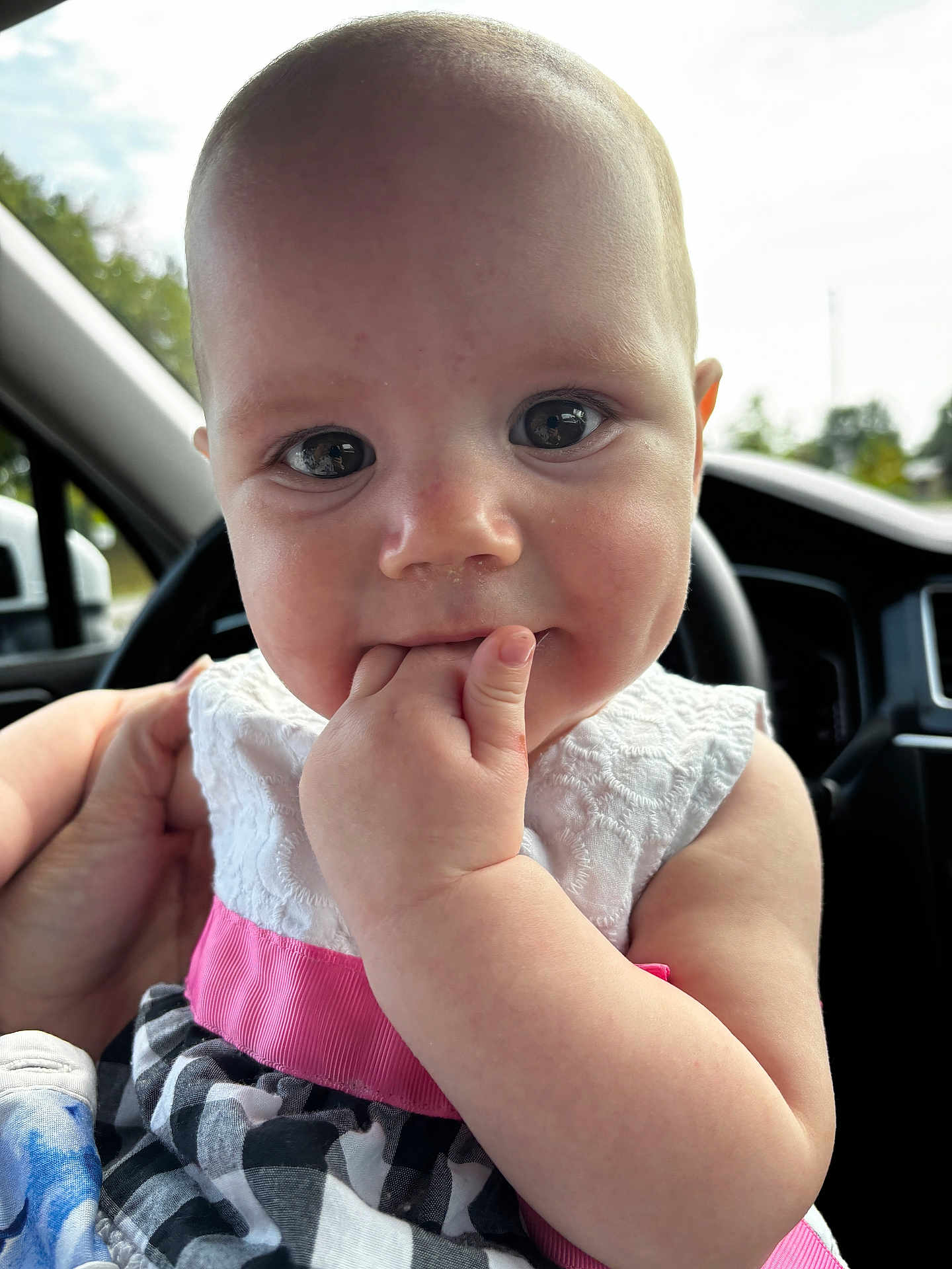 Iris is registered to the contest to win money with this photo: baby, car_interior, cheeks, child, clothing, cute, daylight, dress, face, fingers, hand, holding, infant, person, pink, portrait, seat, skin, white, window