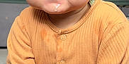 Azaan is registered to the contest to win money with this photo: baby, infant, child, onesie, orange_clothing, sitting, drool, cute, face, hands, feet, portrait, indoor, person, young_child, expression, closeup, skin, head, eyes