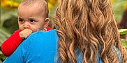 Azaan joined the competition — help win amazing prizes! baby, child, person, adult, hair, blonde, curly_hair, blue_shirt, red_clothing, outdoor, nature, sunflower, greenery, portrait, holding, back_view, face, expression, young_child, daylight