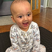 Azaan joined the competition — help win amazing prizes! baby, child, infant, pajamas, mickey_mouse, sitting, happy, smiling, indoor, floor, wood_floor, black_mat, face, hands, cute, clothing, home, door, carpet, person