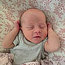 newborn, baby, sleeping, infant, blanket, patterned_blanket, floral_background, peaceful, cute, small_arms, raised_arms, cozy, soft_lighting, indoors, portrait, human, child, resting, closeup, head