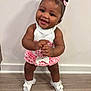 baby, child, smiling, standing, white_socks, bows, pink_dress, white_top, floor, wooden_floor, indoor, happy, cute, person, portrait, toddler, hair_bows, skin, hands, feet