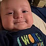 baby, smiling, face, closeup, child, infant, tshirt, text, colorful, indoor, bed, blanket, person, happy, cute, portrait, video_call, screen, technology, young