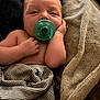 baby, infant, pacifier, blanket, striped_cloth, hand, skin, face, sleepy, resting, cozy, soft_texture, newborn, comfort, closeup, portrait, cute, indoors, child, wrapped