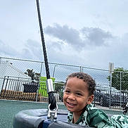 Jayse joined the competition — help win amazing prizes! boy, casual_wear, child, cloudy_sky, curly_hair, daytime, fence, fun, green_clothing, happy, metal, outdoor, park, playground, recreation, rope, smiling, tire_swing, urban, young