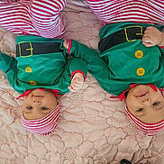Amaya And Ariana is registered to the contest to win money with this photo: baby, infant, twin, child, green_clothing, striped_hat, red_and_white, cute, smiling, lying_down, quilt, bedspread, holiday_costume, festive, adorable, toddler, face, portrait, indoor, cozy