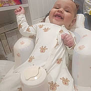 Amaya And Ariana is registered to the contest to win money with this photo: baby, infant, smiling, onesie, reindeer_pattern, cushioned_chair, drool, indoor, happy, child, face, person, furniture, board_game, shelf, toy, cozy, cute, clothing, relaxing