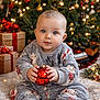 baby, celebration, child, christmas_ornament, christmas_tree, cozy, cute, decorations, face, festive, gift, holiday, indoor, lights, pajamas, present, sitting, smiling, toy_train, winter