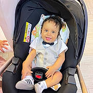 Aylan participe au concours pour gagner de l'argent avec cette photo : baby, infant, child, car_seat, stroller, bow_tie, vest, smile, happy, sneakers, shoes, buckle, canopy, fabric, hand, hair, floor, seat, pattern, portrait