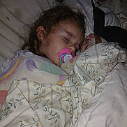 Maddie is registered to the contest to win money with this photo: child, baby, sleeping, blanket, pacifier, bed, cozy, indoor, portrait, face, hair, comfort, pajamas, rest, peaceful, soft, floral_pattern, pastel_colors, toddler, sleep