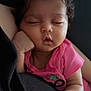 baby, sleeping, curly_hair, pink_shirt, hand, face, infant, resting, cute, peaceful, closed_eyes, skin, portrait, child, indoor, cozy, soft_light, human, relaxation, tiny_fist