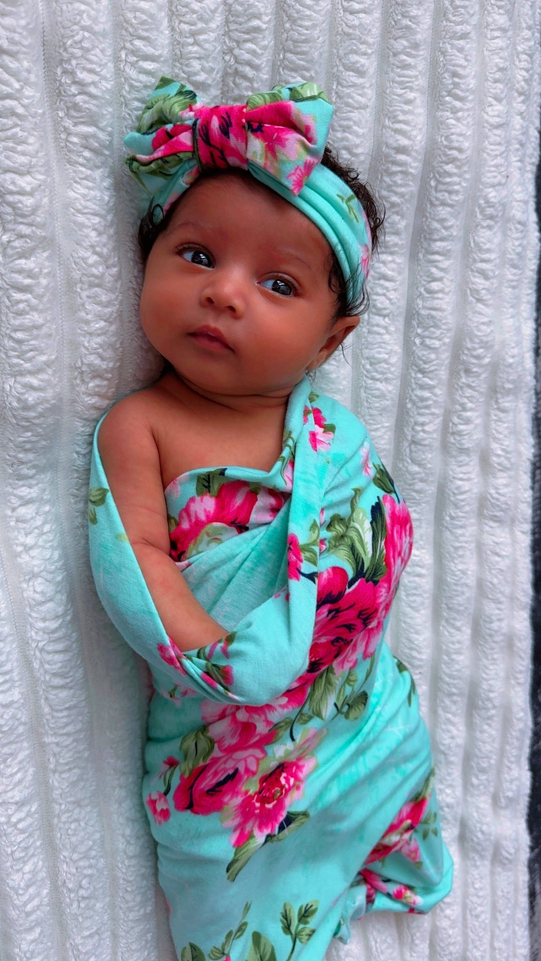 baby, blanket, child, clothing, colorful, curious, cute, eyes, face, floral_pattern, headband, indoors, infant, lying_down, newborn, portrait, skin, soft, texture, wrapped