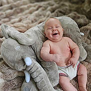 Loukas is registered to the contest to win money with this photo: baby, babylaughing, blanket, bodypart, clothing, couch, face, finger, furniture, glove, hand, happy, head, laughing, newborn, person, photography, portrait, quilt, smile