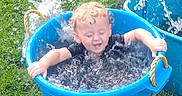 Douglas joined the competition — help win amazing prizes! child, toddler, water, splashing, blue_tub, outdoor, grass, garden, curly_hair, play, summer, fun, happy, water_droplets, plastic_tub, greenery, daylight, person, recreation, leisure