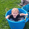 Douglas is registered to the contest to win money with this photo: toddler, child, blue_tub, water, grass, outdoor, curly_hair, smiling, playing, garden, handles, greenery, summer, fun, nature, happy, person, young_child, daylight, casual