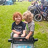 child, toddler, toy_car, curly_hair, grass, bicycle, outdoor, play, greenery, smile, fun, summer, park, vehicle, garden, happy, person, casual_clothing, daylight, nature