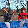 Shane is registered to the contest to win money with this photo: child, children, playground, toy, outdoor, park, blue_structure, red_jacket, curly_hair, grass, trees, smiling, happy, casual_clothing, daytime, play, fun, friends, nature, recreation