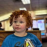Shane joined the competition — help win amazing prizes! child, red_hair, curly_hair, blue_shirt, indoor, portrait, face, person, rosy_cheeks, casual, curious, young_child, background_blur, expression, head_and_shoulders, toddler, cute, looking_away, lighting, skin