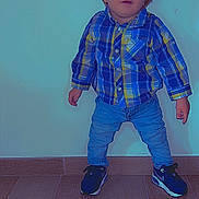 Ezio participe au concours pour gagner de l'argent avec cette photo : toddler, child, plaid_shirt, jeans, sneakers, standing, indoor, wooden_floor, curious_expression, casual_clothing, short_hair, blue_eyes, wall, flooring, portrait, person, young_child, cute, small_hands, footwear