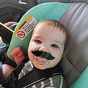 Liam joined the competition — help win amazing prizes! baby, car_seat, pacifier, mustache, child, striped_clothing, seatbelt, indoor, car, infant, cute, face, smiling, young_child, person, seat, warning_label, hand, hair, eyes