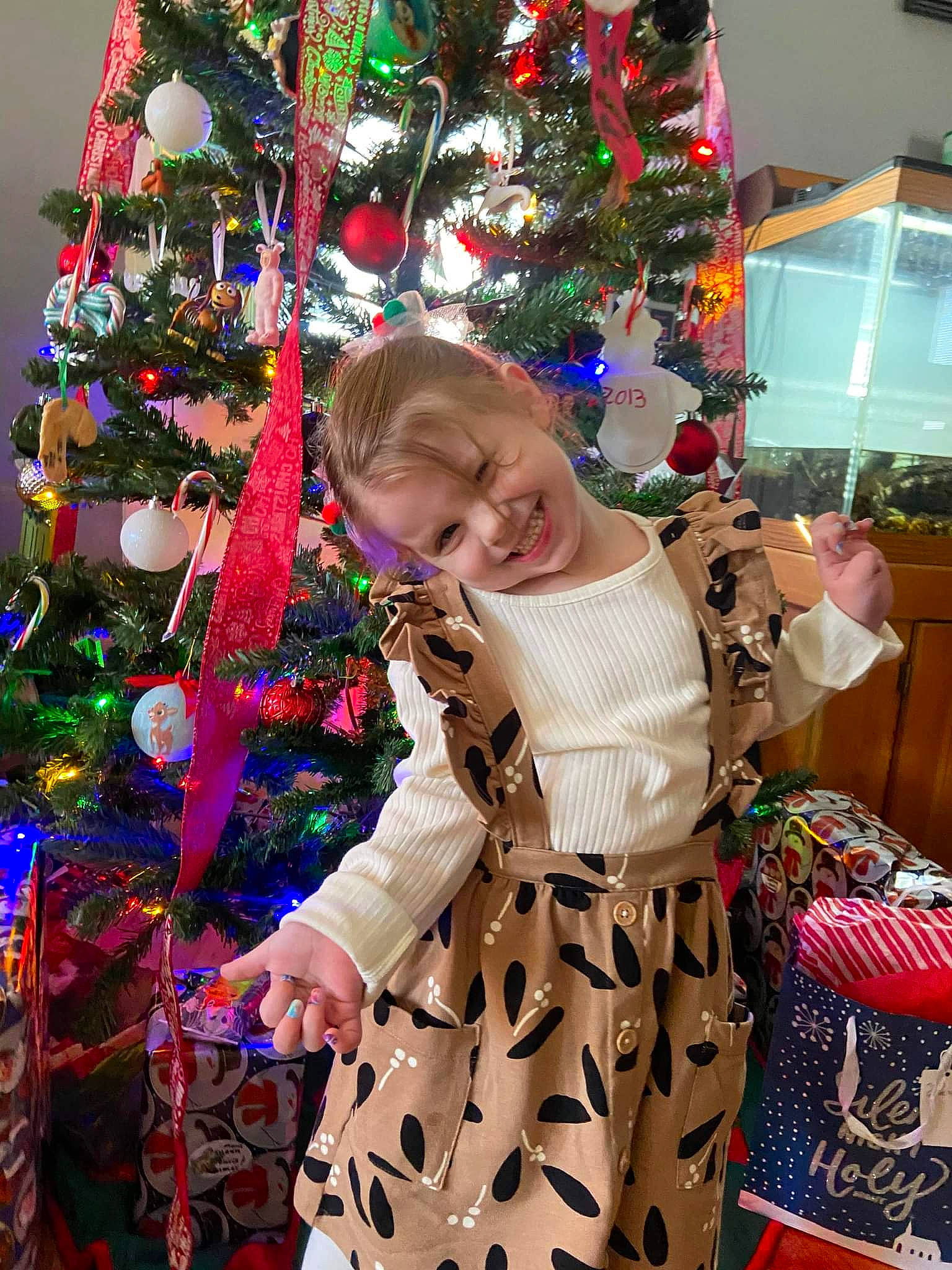 Briana is registered to the contest to win money with this photo: baby_toddler_clothing, christmas, christmas_decoration, christmas_eve, christmas_ornament, christmas_tree, event, fun, happy, holiday, holiday_ornament, joy, magenta, ornament, person, plant, smile, standing, toddler, tradition