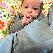 Belladonna joined the competition — help win amazing prizes! baby, child, blanket, pillow, floral_pattern, hand, face, eyes, clothing, indoors, cute, infant, sucking_fingers, portrait, cozy, soft, colorful, expression, resting, young