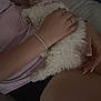 black_shorts, bracelet, casual_clothing, comfort, couch, dim_lighting, dog, fluffy, hand, indoor, intimate, lap, nail_polish, person, pet, pink_shirt, relaxation, snuggling, soft_texture, white_dog