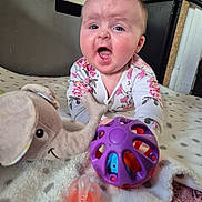 Oliwia joined the competition — help win amazing prizes! baby, child, infant, toy, stuffed_animal, elephant, ball, pacifier, blanket, polka_dot, floral_clothing, onesie, expression, indoor, carpet, face, hands, playing, cute, happy