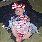 Ava joined the competition — help win amazing prizes! baby, infant, headband, bow, red_white_blue, dress, stars, stripes, blanket, quilt, fuzzy_blanket, lying_down, chubby_legs, clenched_fists, curious_expression, indoors, cute, portrait, child, person