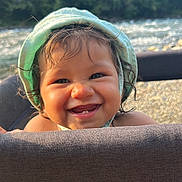 Ohaina participe au concours pour gagner de l'argent avec cette photo : toddler, child, smiling, face, curly_hair, bonnet, playpen, outdoor, nature, trees, water, baby, happy, portrait, skin, headwear, cute, sunlight, daylight, closeup