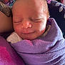 Cali Maye is registered to the contest to win money with this photo: newborn, baby, sleeping, purple_blanket, wrapped, tattoo, arm, peaceful, closeup, face, infant, soft_light, indoors, resting, skin, person, smile, cozy, cute, portrait