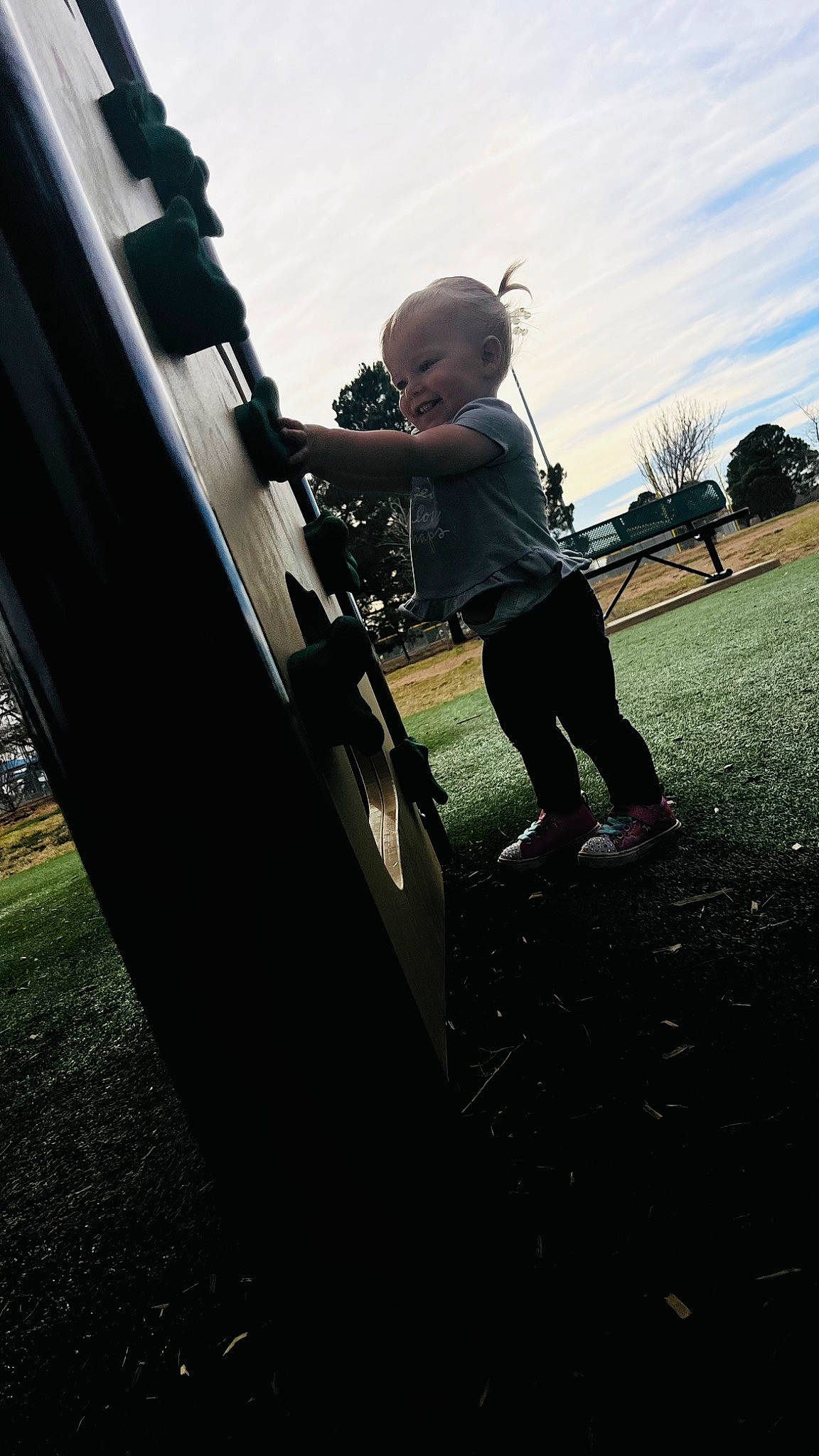 Annabelle is registered to the contest to win money with this photo: automotive_exterior, automotive_tire, automotive_wheel_system, bumper, city, cloud, flash_photography, fun, grass, human_leg, leisure, outdoor_play_equipment, person, playground, recreation, rolling, sky, swing, toddler, tree