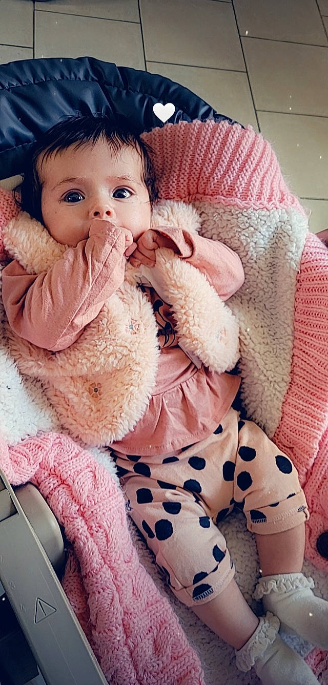 Kim participe au concours pour gagner de l'argent avec cette photo : arm, baby, baby_toddler_clothing, cheek, comfort, dress, eye, eyelash, human, iris, lap, lip, mammal, organ, person, pink, skin, sleeve, textile, toddler