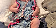 Paisley is registered to the contest to win money with this photo: baby, infant, pacifier, sunglasses, bow, denim_dress, blue_shoes, bed, pillow, blanket, indoor, cute, fashion, child, person, relaxing, resting, accessory, pink, casual