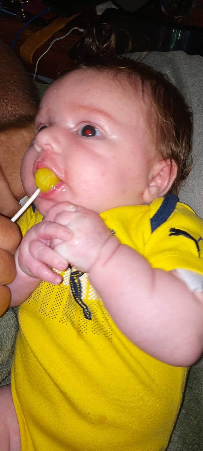 Owen is registered to the contest to win money with this photo: arm, baby, baby_toddler_clothing, cheek, ear, eyelash, finger, gesture, human_body, iris, lip, mouth, nail, neck, nose, orange, person, skin, thumb, toddler