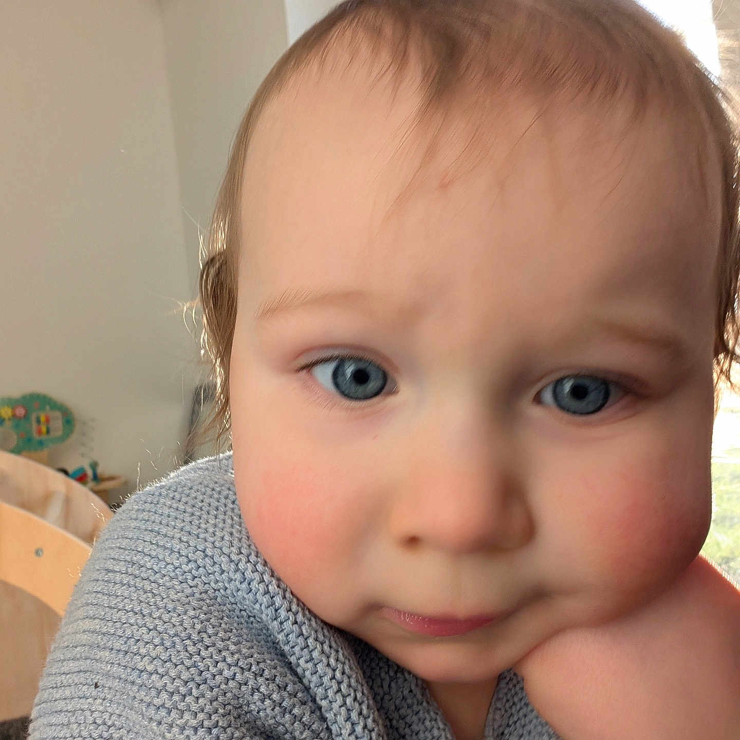 Noah participe au concours pour gagner de l'argent avec cette photo : baby, blue_eyes, child, close_up, cozy, cute, face, furniture, hair, hand, indoor, knitted_sweater, person, portrait, rosy_cheeks, skin, thoughtful, toddler, toy, window