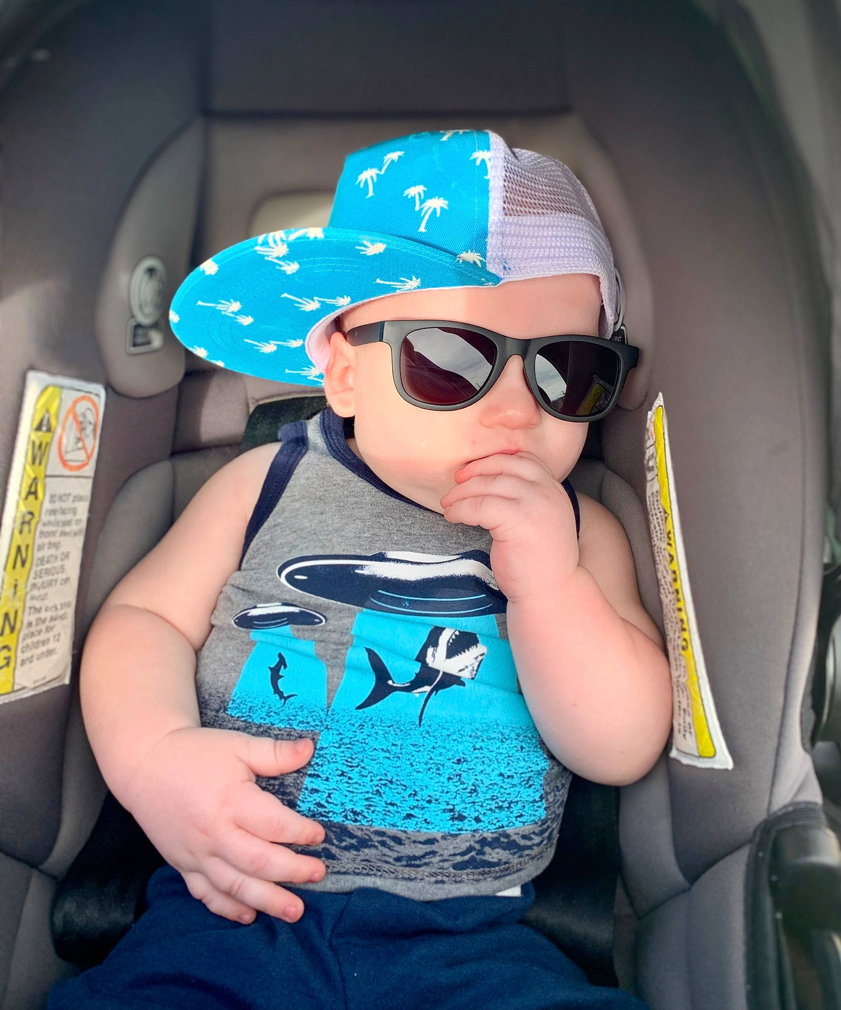 Easton is registered to the contest to win money with this photo: arm, automotive_design, baby_toddler_clothing, baseball_cap, blue, cap, car_seat, cool, eyewear, finger, glasses, goggles, hat, headwear, mouth, person, product, sunglasses, t_shirt, toddler