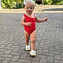 Lyla a rejoint le concours — aidez-le/la à gagner de superbes lots ! toddler, child, swimsuit, red_clothing, walking, outdoor, paved_path, shoes, white_shoes, bows, happy, smiling, blond_hair, short_hair, nature, greenery, sunlight, daytime, person, portrait