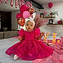 toddler, pink_dress, headband, balloons, birthday, table, marquee_letters, decorations, pink_theme, living_room, couch, plants, photos, celebration, party, fabric, indoor, child, smiling, festive