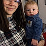 baby, blue_eyes, casual_clothing, child, cute, denim_jacket, family, glasses, holding, home, human, indoor, long_hair, person, plaid_shirt, portrait, smile, toddler, woman, young_adult