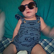Brayden joined the competition — help win amazing prizes! baby, sunglasses, blue_romper, airplane_print, helicopter_print, cushion, plaid_blanket, infant, child, clothing, indoor, blur, pose, cute, cool, relaxing, person, headwear, legs, soft_toy