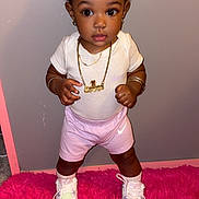Azianna joined the competition — help win amazing prizes! toddler, child, girl, standing, pink_bow, gold_chain, white_shirt, pink_shorts, sneakers, pink_rug, indoor, cute, fashion, jewelry, portrait, young_child, footwear, happy, expressive_eyes, casual_clothing