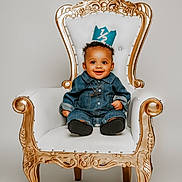 Kiyear is registered to the contest to win money with this photo: baby, child, smiling, denim_outfit, crown, chair, throne, ornate, white, gold, portrait, happy, cute, indoor, seated, young_child, fashion, studio, one_half, celebration