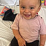 toddler, child, smiling, sitting, indoors, bed, clothing, shorts, tshirt, sock, toy, background, happy, face, person, cute, young_child, home, casual, skin