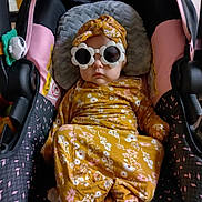 Historia joined the competition — help win amazing prizes! baby, car_seat, sunglasses, flower_shaped, headwrap, yellow_outfit, floral_pattern, infant, child, seatbelt, indoor, cute, fashion, accessory, person, portrait, clothing, baby_clothes, baby_accessory, seat