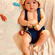 Waylon joined the competition — help win amazing prizes! baby, child, infant, portrait, lying_down, blanket, crocheted_hat, blue_outfit, handmade_clothing, smiling, serious_expression, indoor, soft_lighting, textile, yarn, colorful, bare_feet, seated, cozy, photography