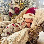 Grayson joined the competition — help win amazing prizes! baby, infant, christmas_tree, santa_hat, blanket, basket, pajamas, holiday, decorations, mittens, indoors, festive, cute, cozy, sleepwear, wooden_floor, soft_lighting, wrapped, seasonal, relaxing